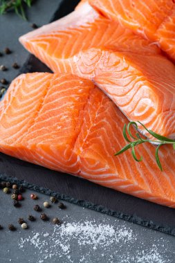 Çiğ somon fileto ve yemek pişirmek için malzemeler, baharatlar ve gri arka planda bitkiler..