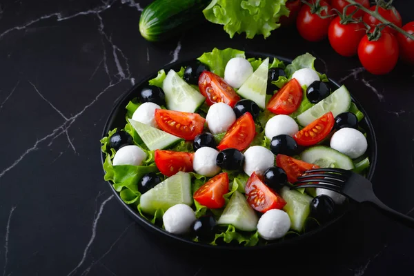 Verse salade met komkommers, tomaten, zwarte olijven en feta of mozzarella kaas — Stockfoto