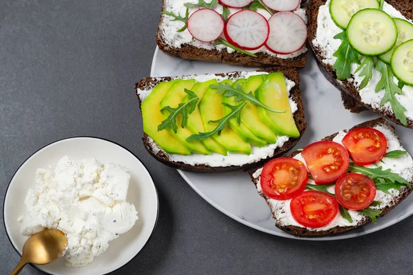 Friska smörgåsar med vit keso, gurka, ruccola, avokado, tomat — Stockfoto