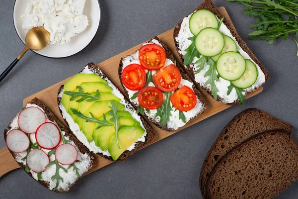 Beyaz süzme peynirli sağlıklı sandviçler, salatalık, roka, avokado, domates. — Stok fotoğraf