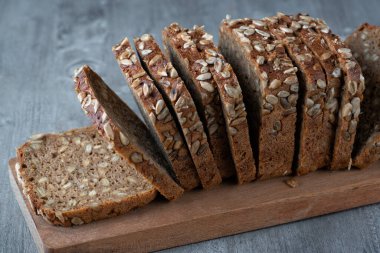 Kesme tahtasında dilimlenmiş çavdar ekmeği. Tohumlu tam tahıllı çavdar ekmeği.