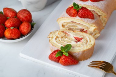 Çilek ve kremayla doldurulmuş tatlı rulo çilek, toz şeker ve nane yapraklarıyla süslenmiş.