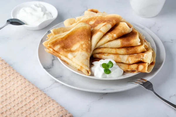 Stapel Russische dunne pannenkoeken blini met verse zure room — Stockfoto