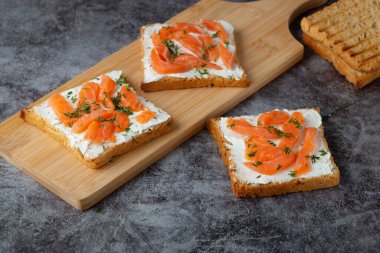 Ev yapımı ekmek ahşap bir kesim tahtasından peynir, somon ve otlarla.