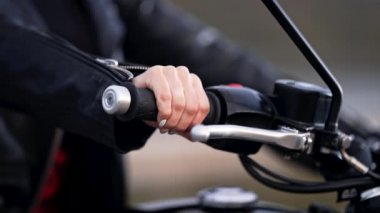 Dişi motosikletçi, şehirde dikilirken ivmeölçer kolu büker. Klasik kafe yarışçılarının kültür ve estetiği, klasik motosiklet.