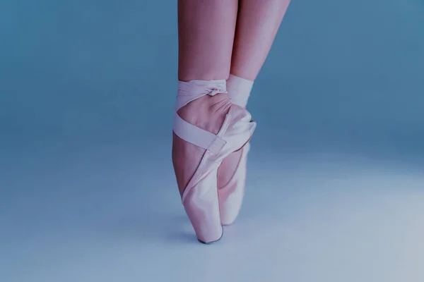 Dançarinas de balé pés, como ela pratica em exercícios de sapatos pontiagudos em fundo azul. Pernas de mulheres bonitas. bailarina mostra clássico ballet pas. — Fotografia de Stock