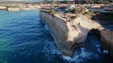 Canal DAmore - Aşk Kanalı, el sallayan turistler. Mavi deniz suyuyla cennetin kumsalına giden hava aracı görüntüsü. Korfu adası, Yunanistan. Yüksek sarp kayalıkları ve dalgaları olan deniz manzarası. 
