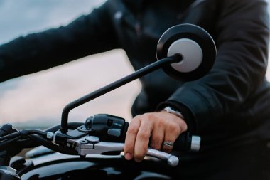 Erkek motosikletçi şehirde dikilirken ivmeölçer kolu büker. Klasik kafe yarışçılarının kültür ve estetiği, klasik motosiklet.