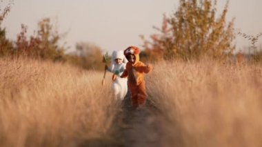 Güzel çocuklar eğleniyor. Erkekler sonbahar doğasında koşuyor. Aslan ve tavşan kostümlü küçük arkadaşlar. Cadılar Bayramı, şeker mi şaka mı? Aile, mutluluk, kardeş kavramı.