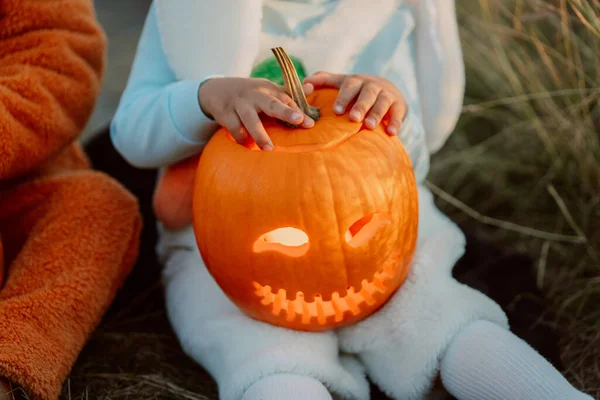 Niño sentado con calabaza tallada. Bebé pequeño con traje de conejito blanco. Halloween, truco o trato concepto. Símbolo de toda la víspera sagrada — Foto de Stock