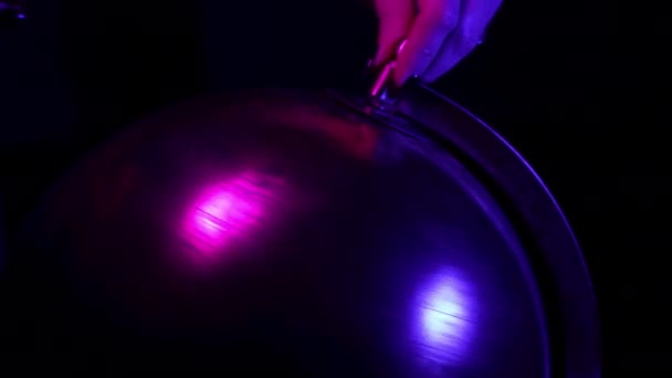 Weibliche Hand dreht sich im Dunkeln unter farbigem Neonlicht um den Globus. Unser Planet, Weltkarte, geografisches Bildungskonzept. — Stockvideo