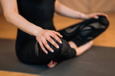 Siyahlı kadın ışık stüdyosu sınıfında yoga yapıyor. Lotus poz verip meditasyon yapan bir kız. Sağlık yaşam tarzı kavramı