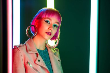 Neon ışığı altında boyalı pembe saç stili olan çekici bir kadının portresi. Gece kulübü, modaya uygun kıyafet. Gençlik, Zoomer Z jenerasyonu.
