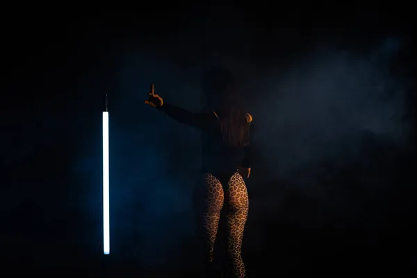 Oigenkännlig kvinna visar en gest - vänta i rökig mörk studio. Sexig outfit - stringtrosa och leopardstrumpbyxor. Damen med uppumpade skinkor — Stockfoto