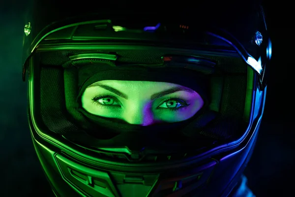 Young female motorcyclist woman in motorcycle helmet. Driver biker looking to camera under glowing colorful neon light with smoke or steam at night. Amazing aesthetic portrait. — Stock Photo, Image