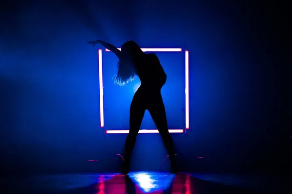 Silhuett av sexig kvinna dansar på glödande fyrkantig led lampor bakgrund. Hon ser förförisk ut. Sexiga kläder. Blå rökig studio. — Stockfoto