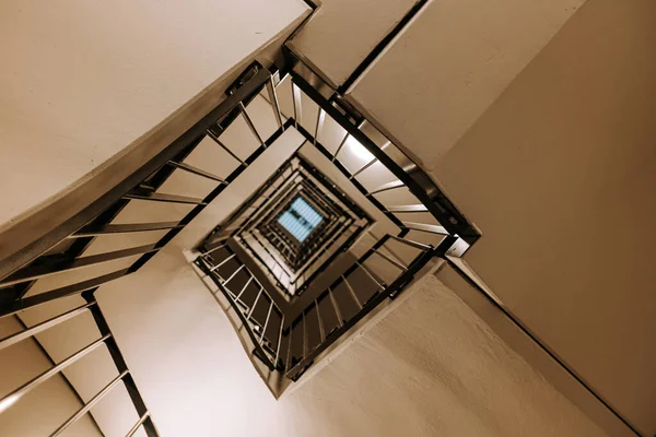 Abstrakcyjny fragment wnętrza kwadratowego piętra schodów w nowoczesnym budynku. Kamera spogląda w górę budynku. Kontekst klatki schodowej, element architektoniczny — Zdjęcie stockowe