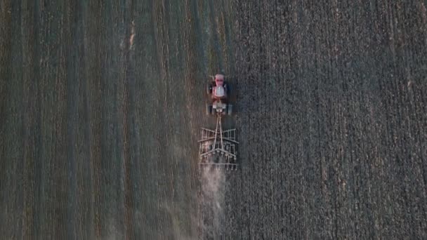 Letecký pohled na zemědělské stroje pracující na obdělávaném poli. Výsev nebo trýznivý koncept. Moderní zemědělský traktor připravuje půdu pro setí plodin. Záběry dronů. — Stock video