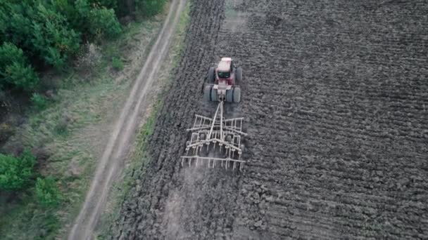 Drón nyomkövető lövés mezőgazdasági traktor szántás száraz területen begyűjtése után betakarítás, pillére por nyomokat mögött. A mezőgazdasági természetes idénymunkák légi rálátása. Szívszaggató koncepció. — Stock videók