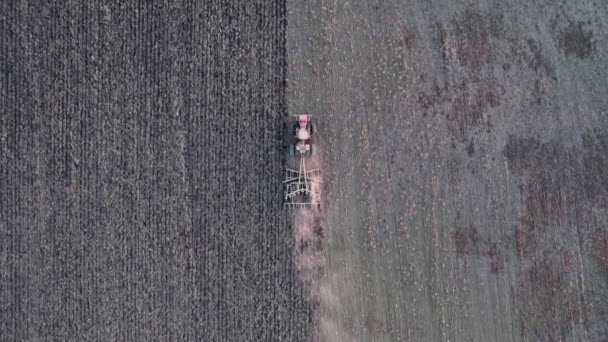 Letecký pohled na zemědělské stroje pracující na obdělávaném poli. Výsev nebo trýznivý koncept. Moderní zemědělský traktor připravuje půdu pro setí plodin. Záběry dronů. — Stock video
