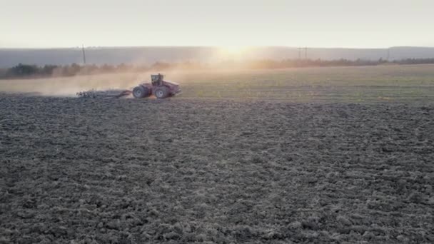 Drone tiro de seguimiento de tractor agrícola arando campo seco después de recoger la cosecha, pilar de senderos de polvo detrás. Vista aérea de las obras agrícolas naturales de temporada. Concepto desgarrador. — Vídeos de Stock