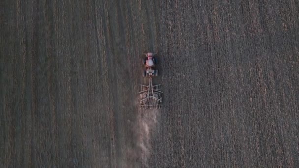Vrcholový záběr zemědělského traktoru orajícího suché pole po sklizni. Letecký pohled na přírodní zemědělské sezónní práce. Trýznivý koncept. — Stock video