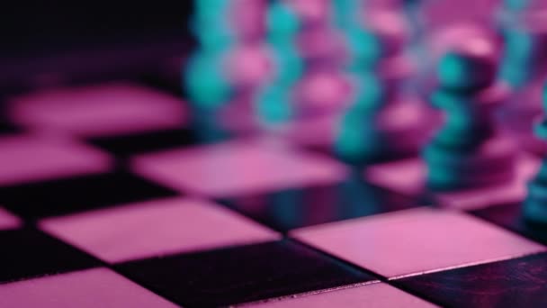 Dolly shot of chess pieces on wooden chessboard under neon colorful light - rose et bleu. Jeu de stratégie. Travail d'équipe, succès, intelligence concept sportif. — Video