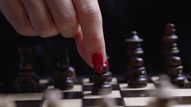 Žena hráč hraje deskové zpravodajské hry - dřevěné šachy. Detailní pohled na ženskou paži s červenými nehty pohybuje šachovou figurkou pěšec, první tah. Sport, koncepce strategie úspěchu. — Stock video