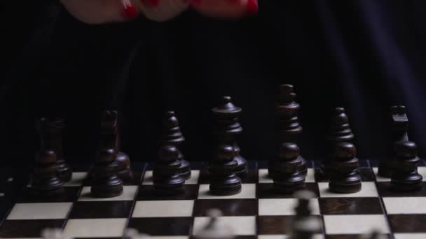 Женщина играет в настольный интеллект - деревянные шахматы. Крупный план женской руки с красными ногтями перемещает пешку шахматной фигуры, первый ход. Спорт, концепция стратегии успеха. — стоковое видео