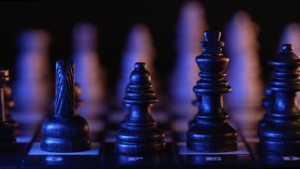Board intelligence spel - träschack under neon färgglada ljus - gul och blå. Närbild av bitar på schackbrädet på mörk bakgrund. Affärslösningar, idrott, framgångskoncept. — Stockvideo