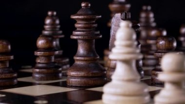 Satranç tahtasındaki taşlara yakından bak. Tahta zeka oyunu, karanlık arka planda tahta satranç. İş çözümleri, meydan okuma, spor, başarı stratejisi kavramı.