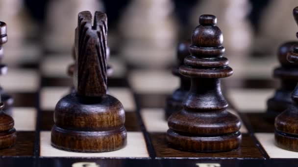 Widok z bliska na figury szachownicy. Gra planszowa inteligencja - szachy drewniane na ciemnym tle. Rozwiązania biznesowe, wyzwania, sport, koncepcja strategii sukcesu. — Wideo stockowe