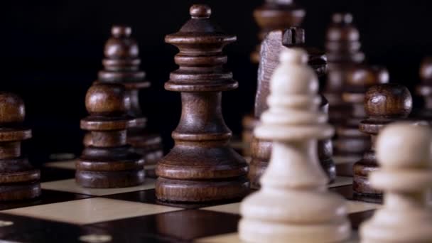 Vista de perto das peças no tabuleiro de xadrez. Jogo de inteligência de bordo - xadrez de madeira em fundo escuro. Soluções empresariais, desafio, esporte, conceito de estratégia de sucesso. — Vídeo de Stock
