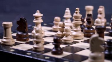 Satranç tahtasındaki taşların kaygan görüntüsü. Tahta zeka oyunu, karanlık arka planda tahta satranç. İş çözümleri, meydan okuma, spor, başarı stratejisi kavramı.