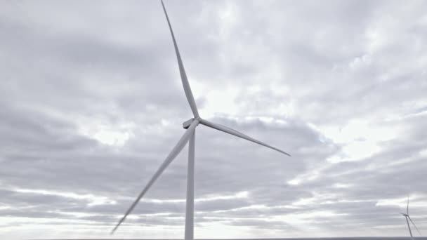 曇った空の背景に風車を回転させます。空中ドローンの眺め、風力タービンによる再生可能エネルギーのクリーン。 — ストック動画