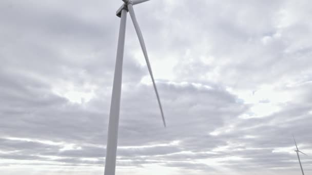 Moulin à vent rotatif sur fond de ciel couvert. Vue aérienne par drone, énergie renouvelable propre produite par les éoliennes. Tourner les pales à pleine vitesse sur une grande ferme en mer ou sur le terrain. Mode de vie alternatif — Video
