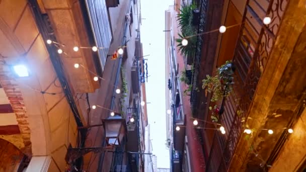 Natal luzes luzes decoração da casa exterior em Barcelona Bairro Gótico. Fachadas de edifícios de apartamentos medievais com guirlandas em rua estreita da Europa. Conceito de viagem. — Vídeo de Stock