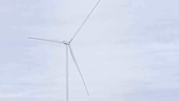 オフショアやフィールドの大規模な農場でフルスピードでブレードを回します。灰色の空の背景に風車を回転させます。風力タービンによる再生可能エネルギーのクリーン化。代替ライフスタイル — ストック動画