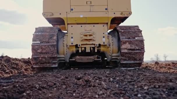Tracking shot of crawler bulldozer working on construction site or quarry. Maquinaria de minería de arcilla móvil, suavizar la superficie de grava para la nueva carretera. Movimiento de tierras, excavaciones, excavaciones en suelos. — Vídeos de Stock