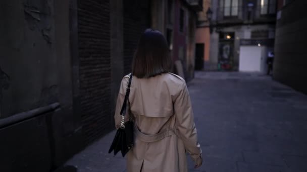 Achteraanzicht van een vrouw die alleen loopt in de Gotische wijk van Barcelona. Oude flatgebouwen, smalle straatjes van Europa. Reizen in de herfst, dame in regenjas. — Stockvideo
