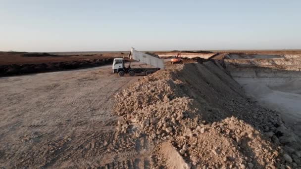 Borravaló a bányában. A teherautó köveket önt ki a testből, miközben a gödörben dolgozik. Drón légi felvétel. Nehézgép-koncepció. — Stock videók
