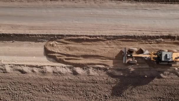 Aerial drone shot of road grader smoothing grava surface for new road. Suelo de nivelación de raspador, trabajando en la construcción. Movimiento de tierras, excavaciones, excavaciones en suelos. — Vídeo de stock