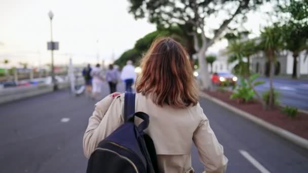 Nierozpoznawalna kobieta spaceruje po ruchliwej ulicy z plecakiem na ramieniu. Studentka wraca po zajęciach z uniwersytetu. Pani turystka spacerująca samotnie w Europie. — Wideo stockowe