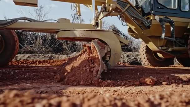 Sledování záběru žluté silniční grader vyhlazování štěrkové plochy pro dálniční silnici. Scraper leveling ground, working at construction. Pohyb země, vykopávky, kopání v půdě. — Stock video