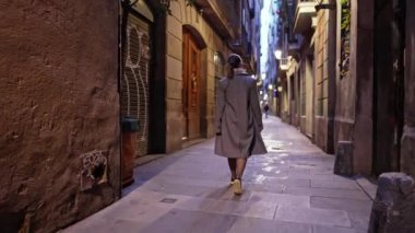Barcelona Gotik Mahallesi 'nde tek başına yürüyen mutlu bir kadın. Eski apartmanlar, Avrupa 'nın dar sokakları. Sonbaharda seyahat eden, paltolu bayan yeni şehri keşfetmekten zevk alır..