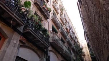 Barcelona 'nın Gotik Mahallesi' nde yeşil balkonları olan eski apartmanlar. Popüler seyahat yeri. Yürüyen kişinin öznel sabit görüntüsü.