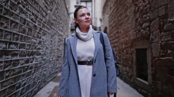 Fiatal nő egyedül sétál a barcelonai gótikus negyedben. Régi lakóépületek, Európa szűk utcái. Ősszel utazva a kabátos hölgy élvezi az új város felfedezését.. — Stock videók