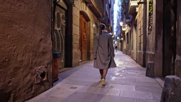 Barcelona Gotik Mahallesi 'nde tek başına yürüyen mutlu bir kadın. Eski apartmanlar, Avrupa 'nın dar sokakları. Sonbaharda seyahat eden, paltolu bayan yeni şehri keşfetmekten zevk alır.. — Stok video