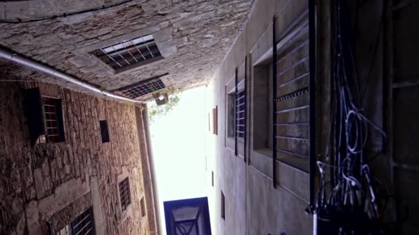 The well of medieval town courtyard. Camera rotation upwards, filming tall buildings in European city. Narrow stone streets — 图库视频影像