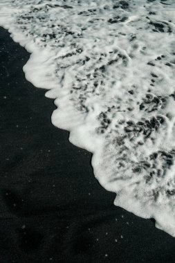 Siyah kanarya kumsalı arka planı. Volkanik kum okyanus dalgalarıyla yıkanır. Bali Adası 'nın inanılmaz doğa manzarası volkanla kaplı..